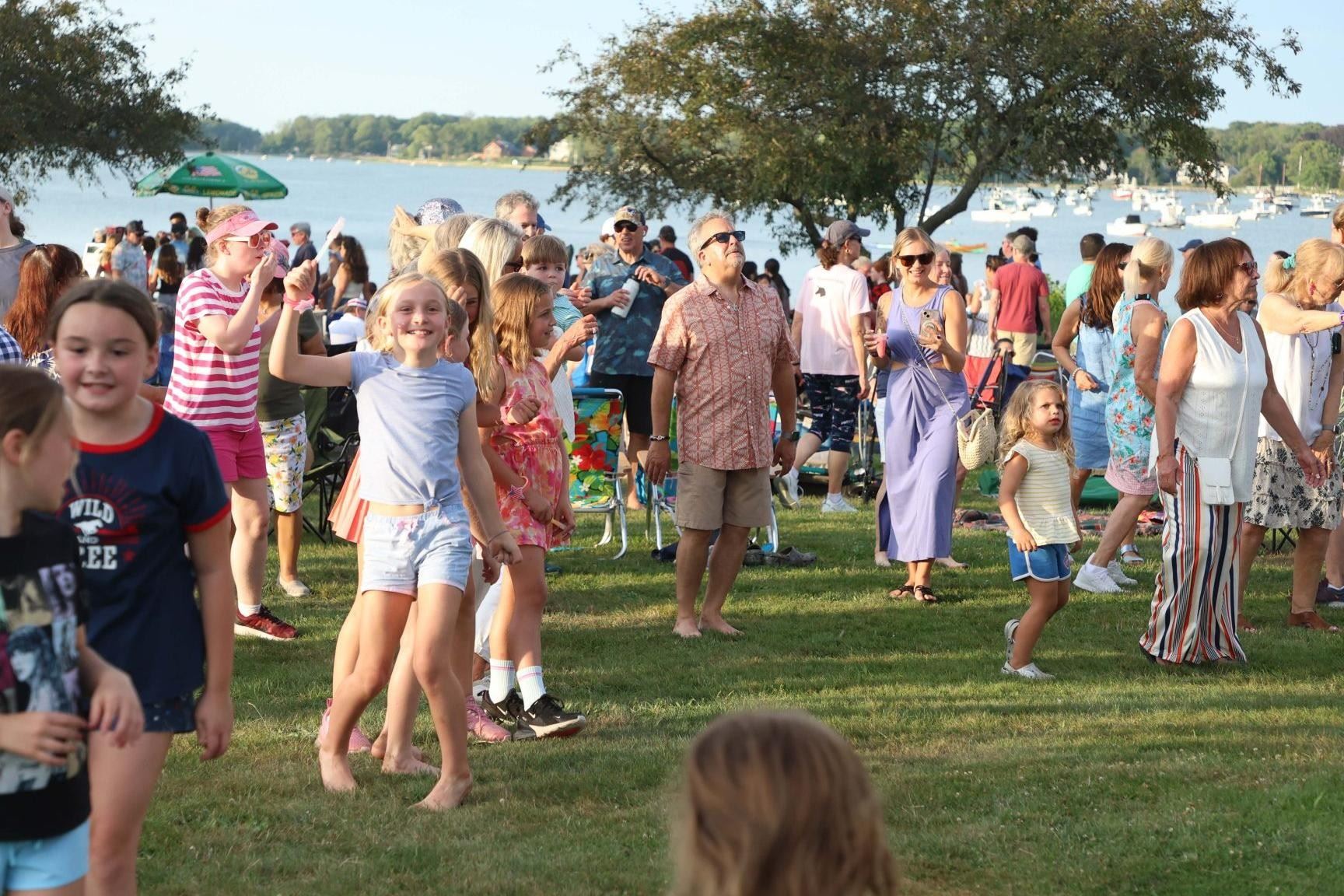 people dancing on grass near water