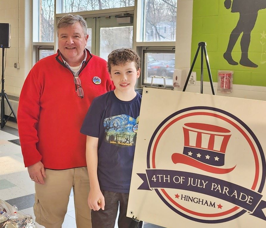 Man and boy standing next to parade sign